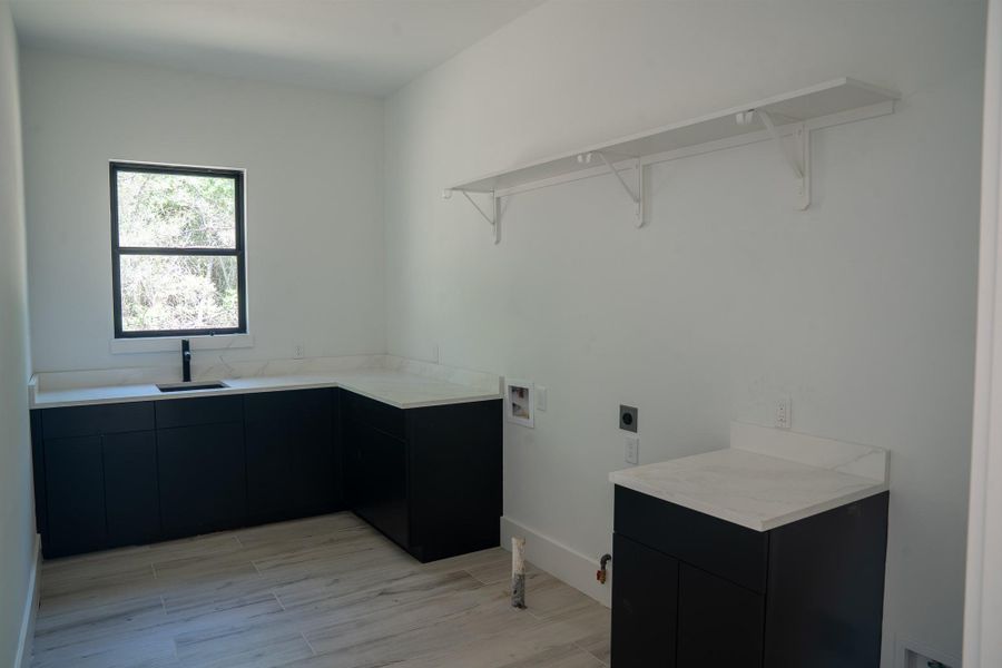 Laundry room featuring ample storage space and a sink.