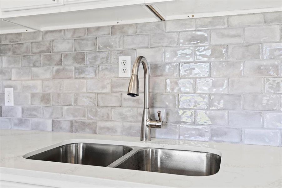 Kitchen view of light  countertops and decorative backsplash