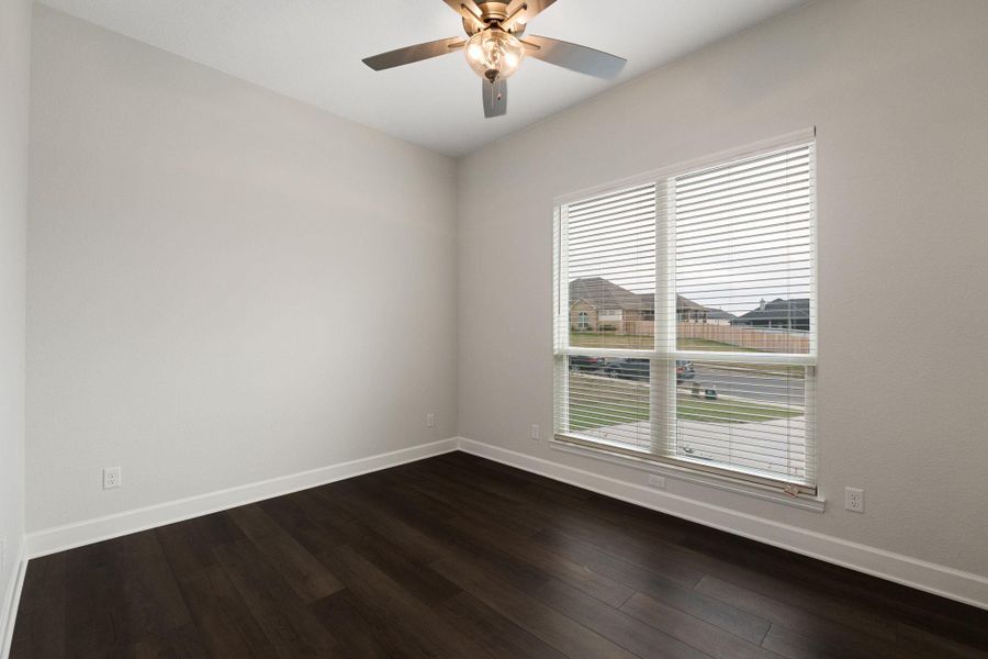 Empty room with dark wood finished floors and a ceiling fan
