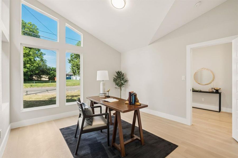 Vaulted ceiling interior space featuring a large window array, wood-finish flooring, and light neutral wall paint Vaulted ceiling interior space featuring a large window array, wood-finish flooring, and light neutral wall paint