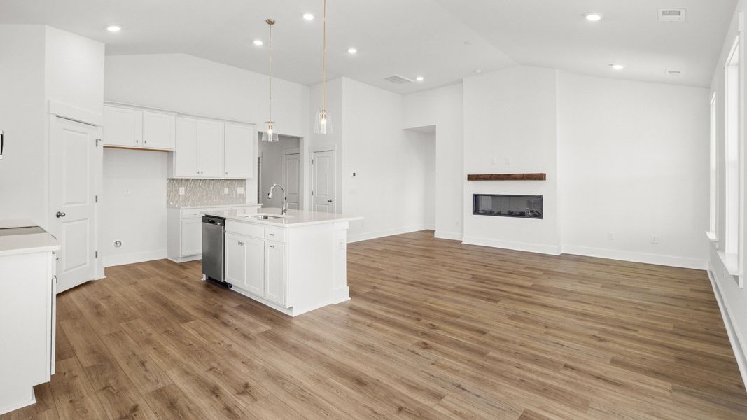 Open living and kitchen with electric fireplace and vaulted ceilings. Open living and kitchen with electric fireplace and vaulted ceilings.