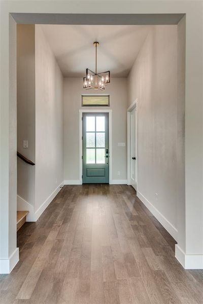 Entrance foyer featuring wood finished floors and a chandelier Entrance foyer featuring wood finished floors and a chandelier