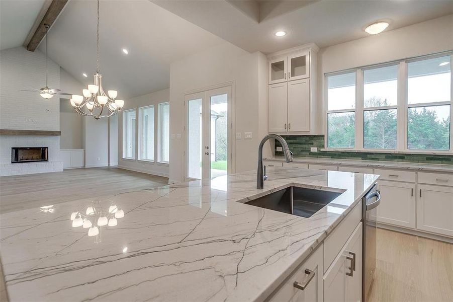 Kitchen featuring lofted ceiling with beams, white cabinetry, sink, and light wood-type flooring