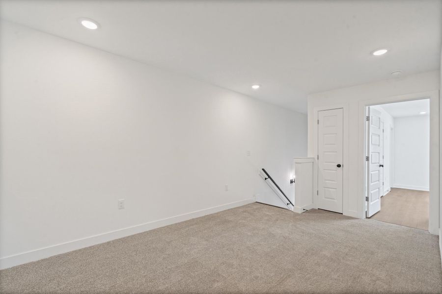 Recessed ceiling lighting illuminates the carpeted flooring and white walls Recessed ceiling lighting illuminates the carpeted flooring and white walls