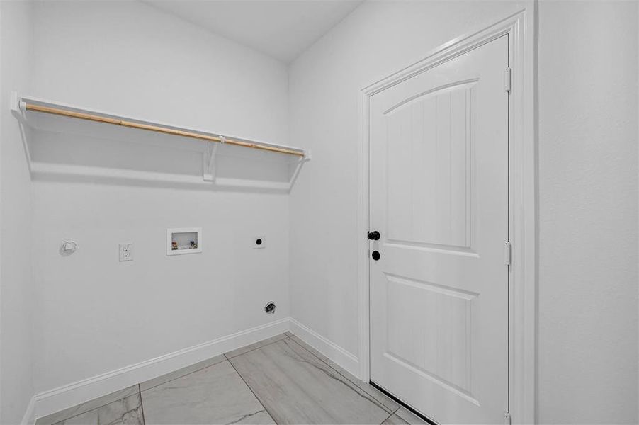 Clothes washing area with washer hookup, light tile patterned flooring, and hookup for an electric dryer