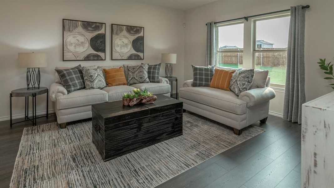 Living area featuring wood-finish flooring, light neutral wall paint, and two windows providing ample natural light