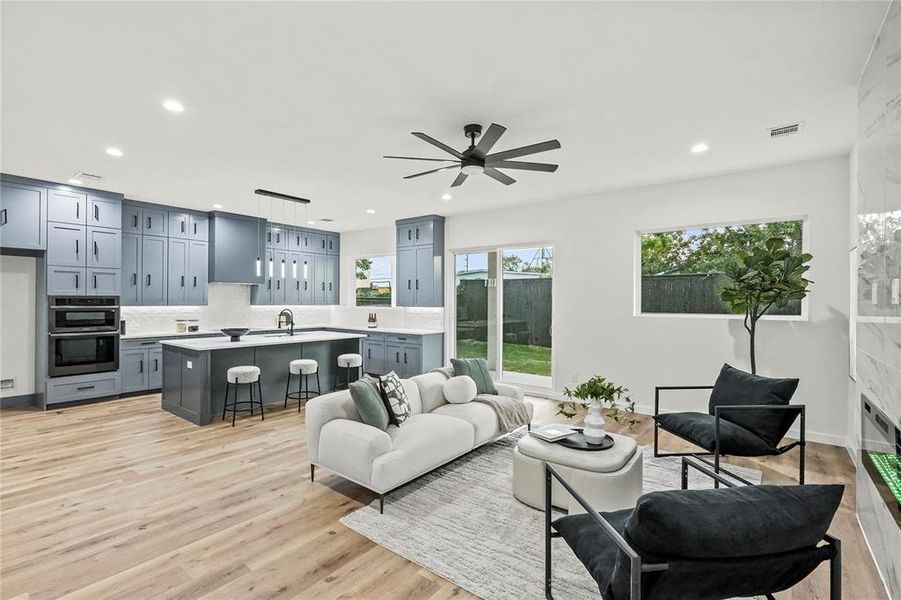 Living room featuring ceiling fan, sink, and light hardwood / wood-style flooring