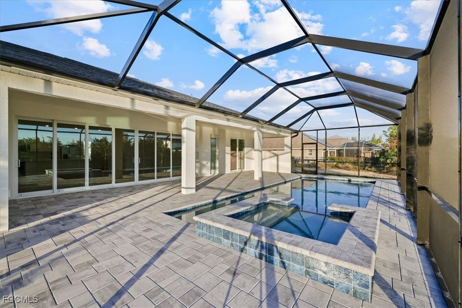 View of swimming pool featuring a sunroom, a pool with connected hot tub, a lanai, and a patio area