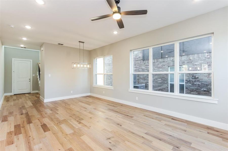 Unfurnished room with ceiling fan with notable chandelier and light wood-type flooring