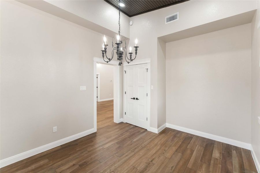 This room can be used as dining or a bonus room with the elegant tile flooring and soft taupe walls, accented by a classic chandelier. The space is finished with white trim and double doors, creating a welcoming entryway.