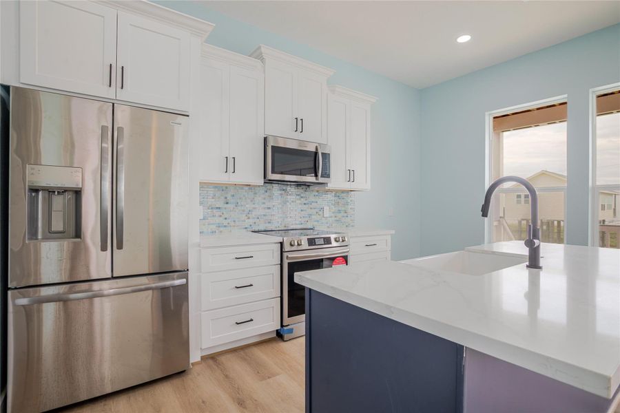 Soft colors in kitchen with white cabinets and modern navy color accent on the large island