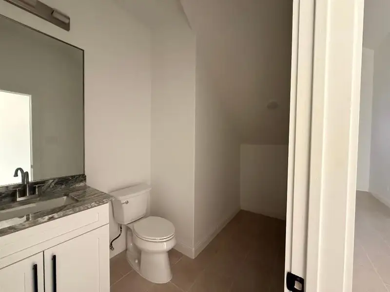 Half bath with vanity and dark tile patterned flooring