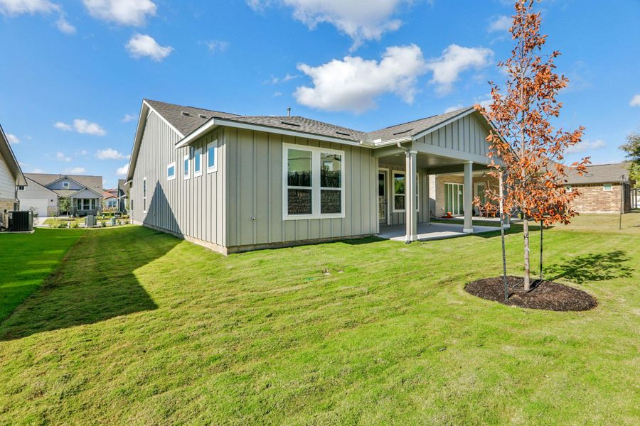 Back of house with a patio area, board and batten siding, a lawn, and a shingled roof Back of house with a patio area, board and batten siding, a lawn, and a shingled roof