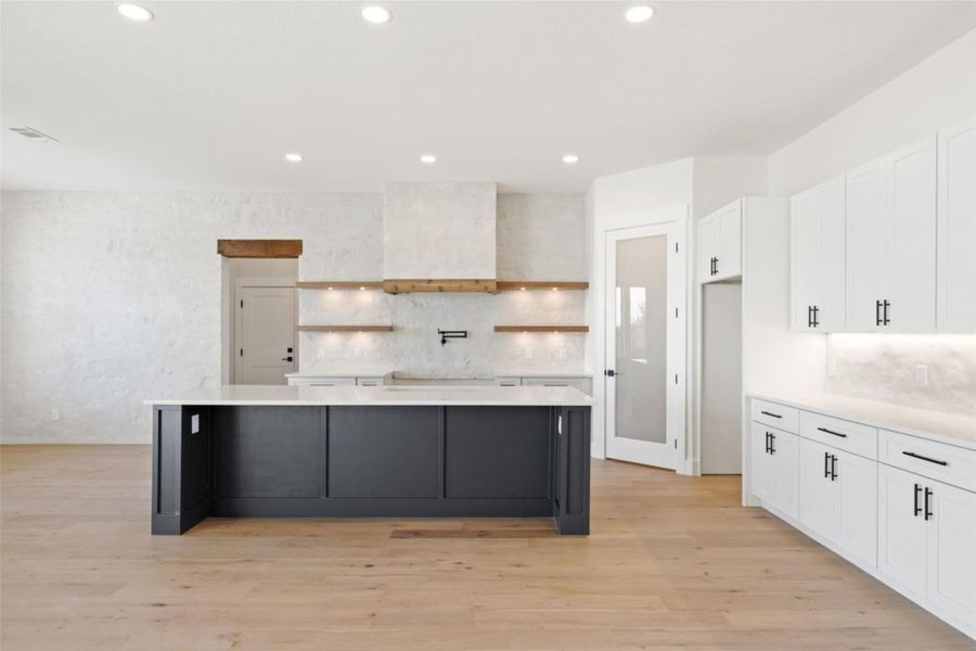 A well-lit kitchen with a spacious island, contemporary white cabinetry, and light wood flooring invites culinary creativity. A well-lit kitchen with a spacious island, contemporary white cabinetry, and light wood flooring invites culinary creativity.