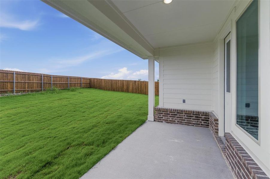 Expansive backyard with a manicured lawn, full privacy fencing, and a concrete patio