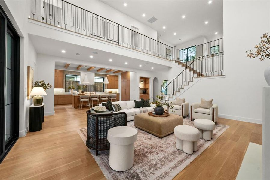 Living area featuring recessed lighting, light wood-style floors, plenty of natural light, stairway, and a towering ceiling Living area featuring recessed lighting, light wood-style floors, plenty of natural light, stairway, and a towering ceiling