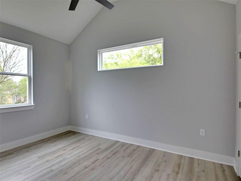 Unfurnished room with lofted ceiling, light wood-type flooring, and ceiling fan