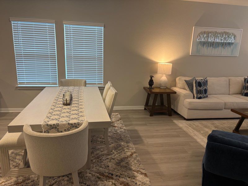 Natural light illuminates this versatile living and dining space, showcasing rich hardwood flooring throughout.