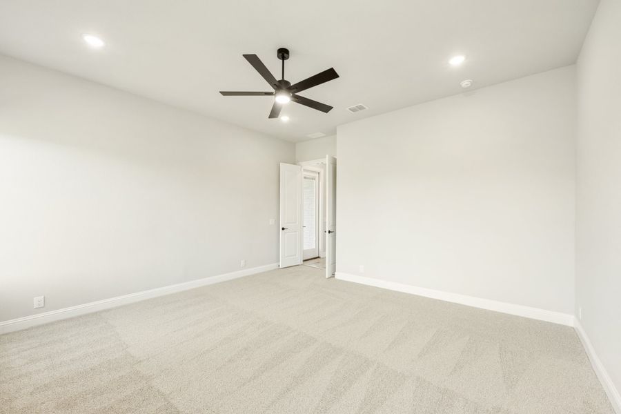 Empty bedroom with beige carpet, white walls, and black ceiling fan with light fixture Empty bedroom with beige carpet, white walls, and black ceiling fan with light fixture