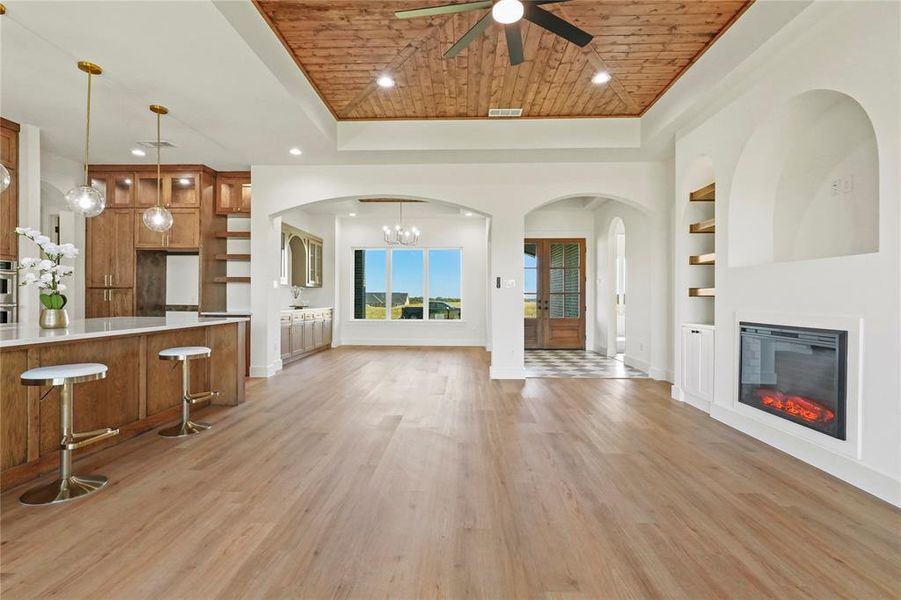 Unfurnished living room with wooden ceiling, recessed lighting, a glass covered fireplace, built in shelves, and light wood finished floors Unfurnished living room with wooden ceiling, recessed lighting, a glass covered fireplace, built in shelves, and light wood finished floors