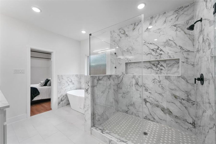 Spacious bathroom featuring a frameless glass shower enclosure with marble-finish tile walls and a built-in shower niche Spacious bathroom featuring a frameless glass shower enclosure with marble-finish tile walls and a built-in shower niche