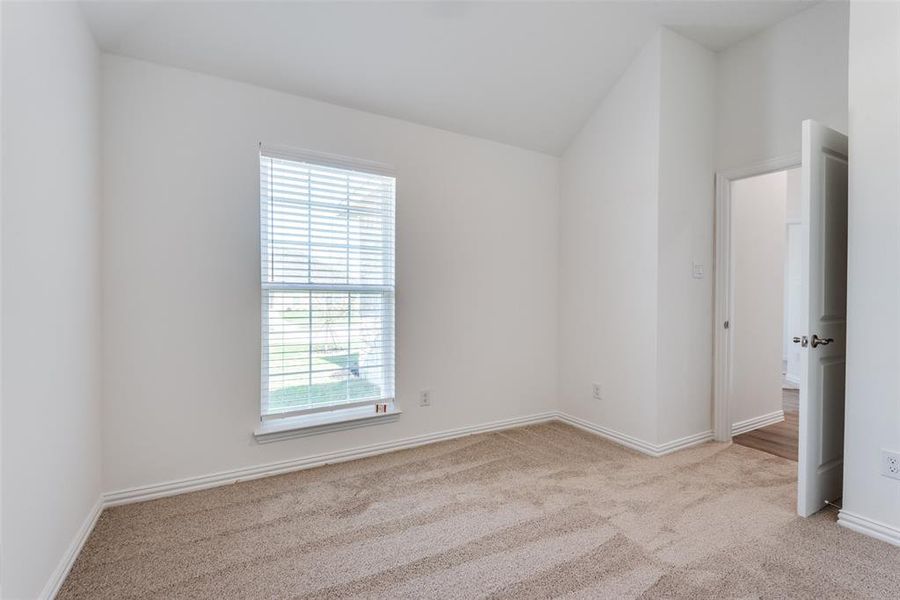 Empty room featuring light carpet and lofted ceiling