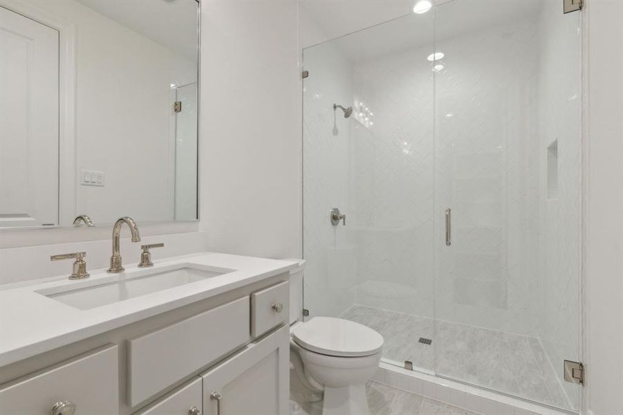 Bathroom featuring walk in shower, vanity, and toilet