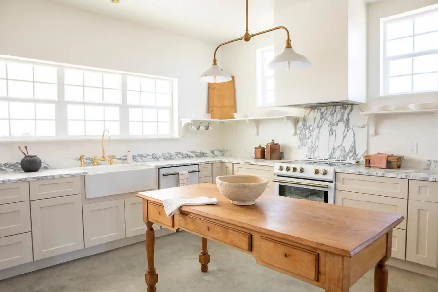 Kitchen with decorative light fixtures, high end range, light stone counters, decorative backsplash, and wall chimney range hood Kitchen with decorative light fixtures, high end range, light stone counters, decorative backsplash, and wall chimney range hood