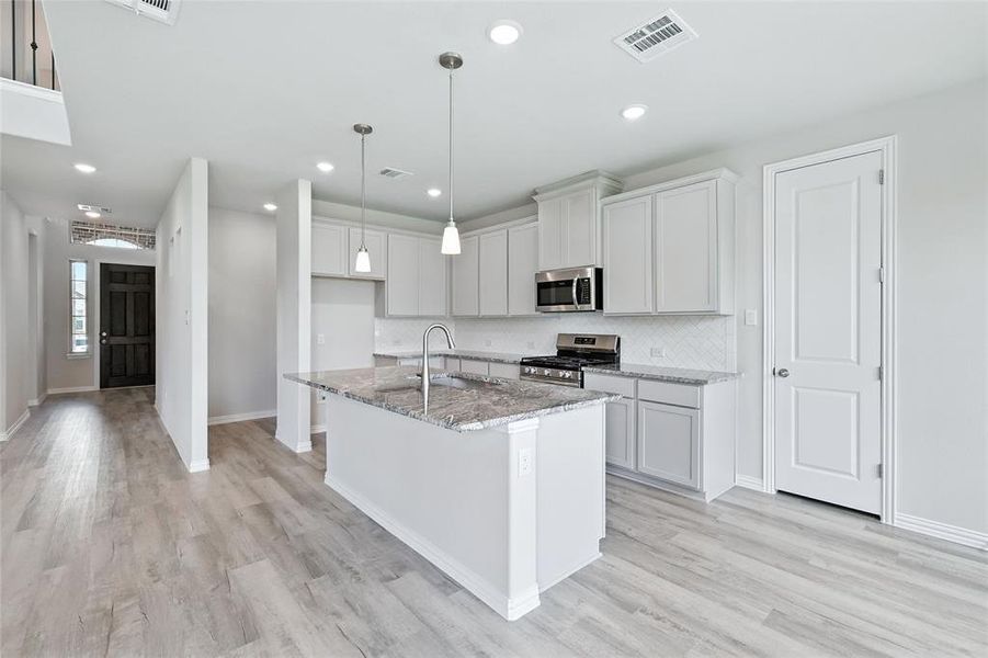 Kitchen with stainless steel appliances, light stone counters, light wood-style flooring, decorative backsplash, and recessed lighting Kitchen with stainless steel appliances, light stone counters, light wood-style flooring, decorative backsplash, and recessed lighting