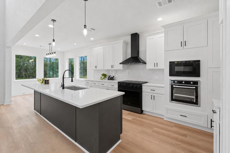 A modern kitchen featuring a large island with a sleek black base and Quartz countertops. The space includes soft closed cabinetry, stainless steel appliances, and pendant lighting. The light wood flooring and open layout create a bright and inviting atmosphere. A modern kitchen featuring a large island with a sleek black base and Quartz countertops. The space includes soft closed cabinetry, stainless steel appliances, and pendant lighting. The light wood flooring and open layout create a bright and inviting atmosphere.