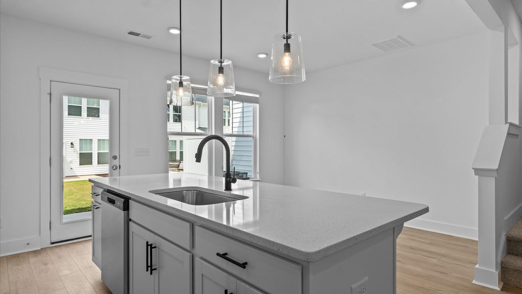 Tasteful design meets functional luxury in this kitchen with a 9-foot island and modern pendant lighting Tasteful design meets functional luxury in this kitchen with a 9-foot island and modern pendant lighting