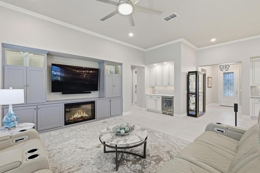 Living area featuring a built-in entertainment center with a fireplace, vaulted ceilings, and crown molding