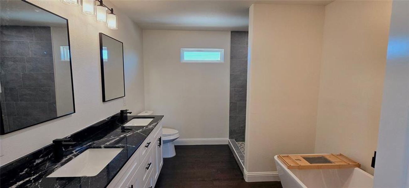 Bathroom with double vanity, walk in shower, dark wood-style floors, and a soaking tub Bathroom with double vanity, walk in shower, dark wood-style floors, and a soaking tub