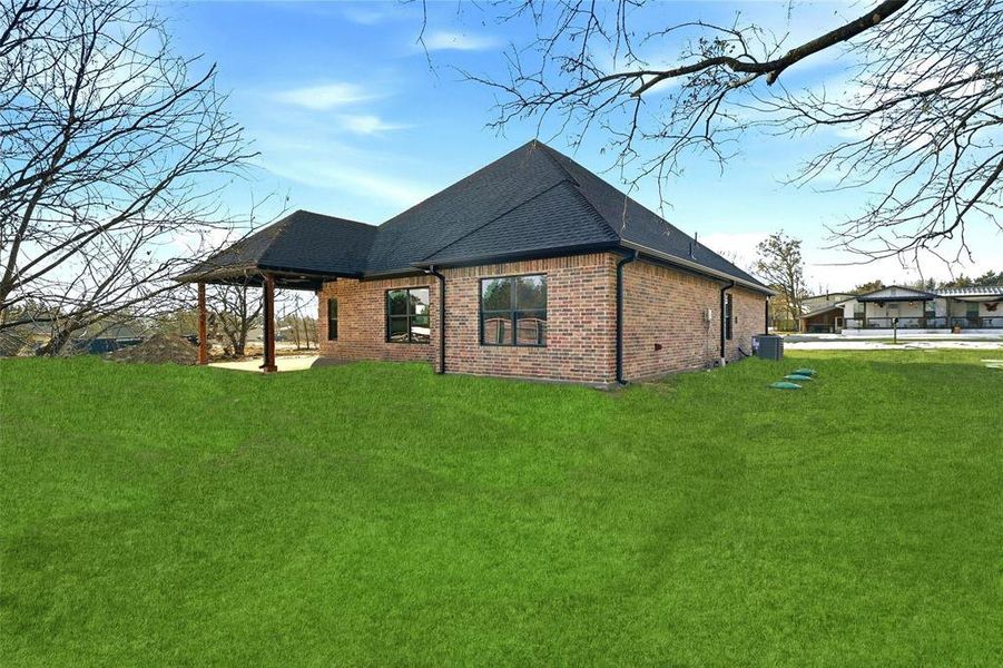 Back of house featuring brick siding, a patio area, a yard, and roof with shingles Back of house featuring brick siding, a patio area, a yard, and roof with shingles