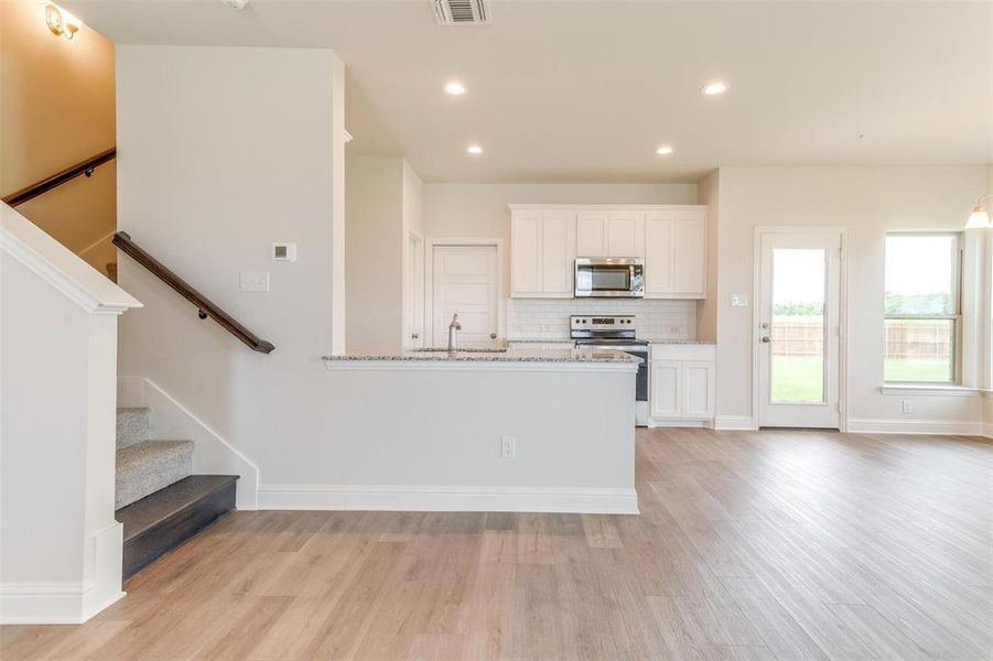 Kitchen featuring white cabinetry, stainless steel appliances, sink, and light stone counters