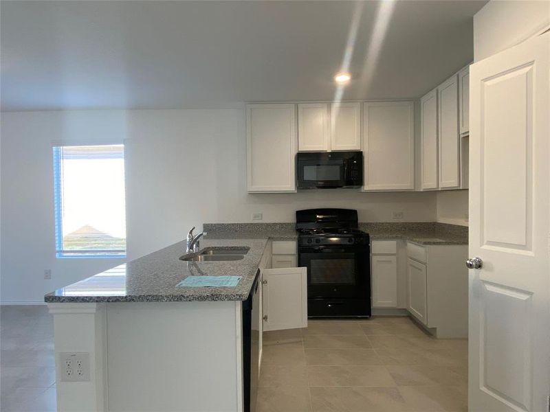 Kitchen with white cabinetry, a sink, a peninsula, and black appliances