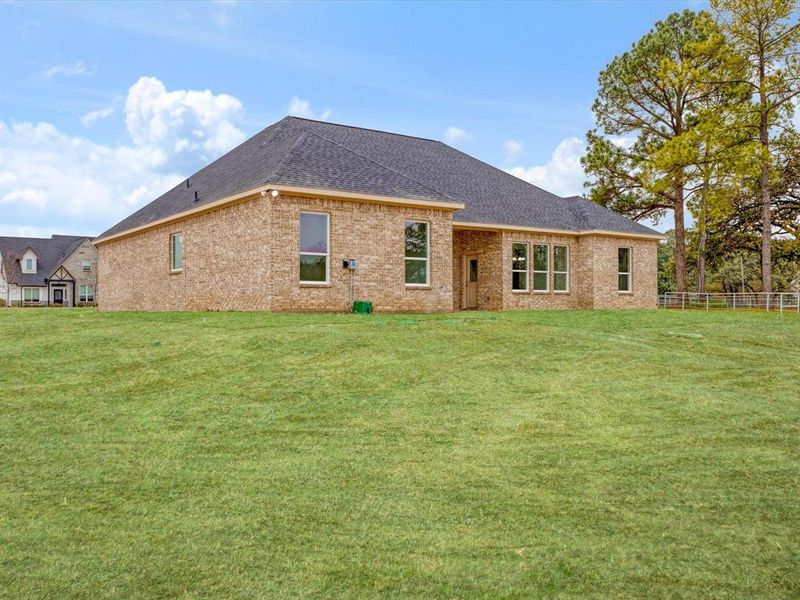 Back of property with a shingled roof, brick siding, and a patio Back of property with a shingled roof, brick siding, and a patio