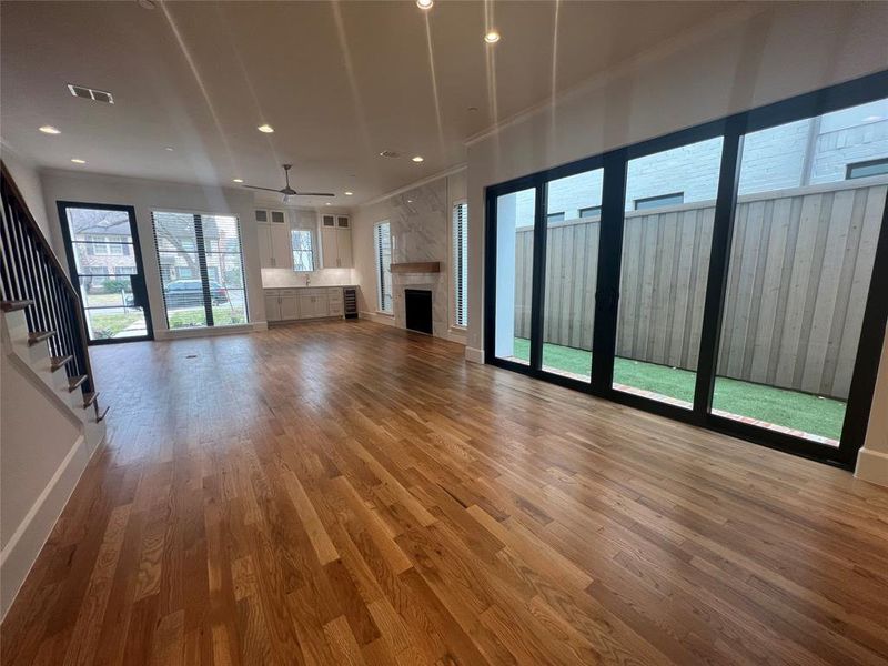 Unfurnished living room with a stone fireplace, wood-type flooring, and ceiling fan