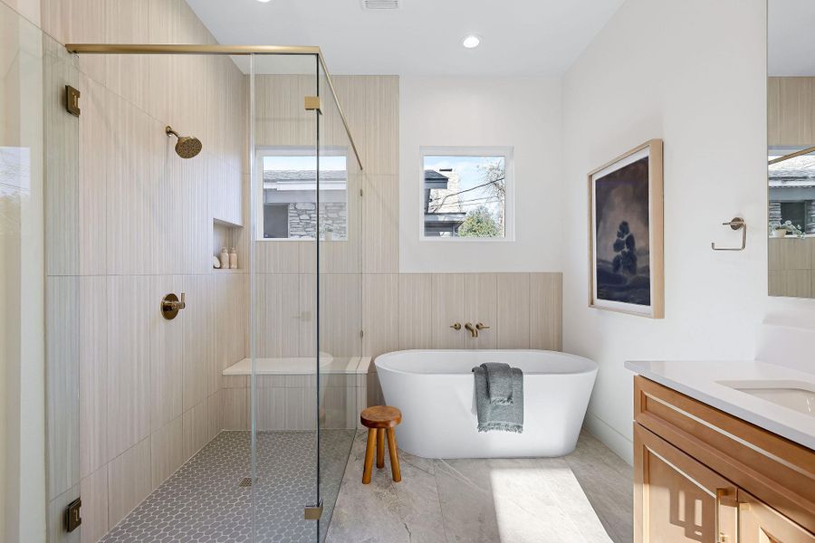Full bath featuring a stall shower, a freestanding bath, and vanity