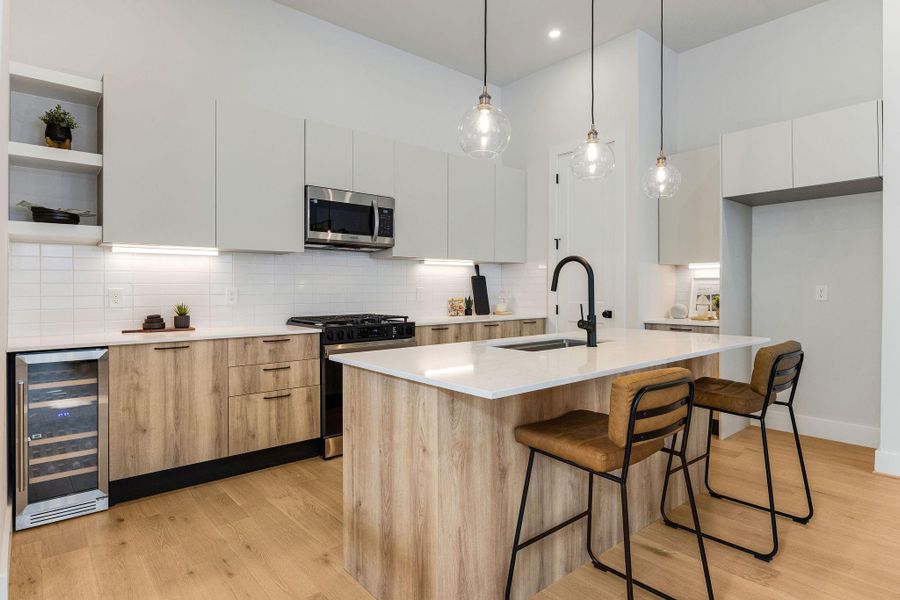 Kitchen features custom flat paneling cabinets, under-cabinet lighting, soft-close cabinetry and drawers, and a wine fridge.