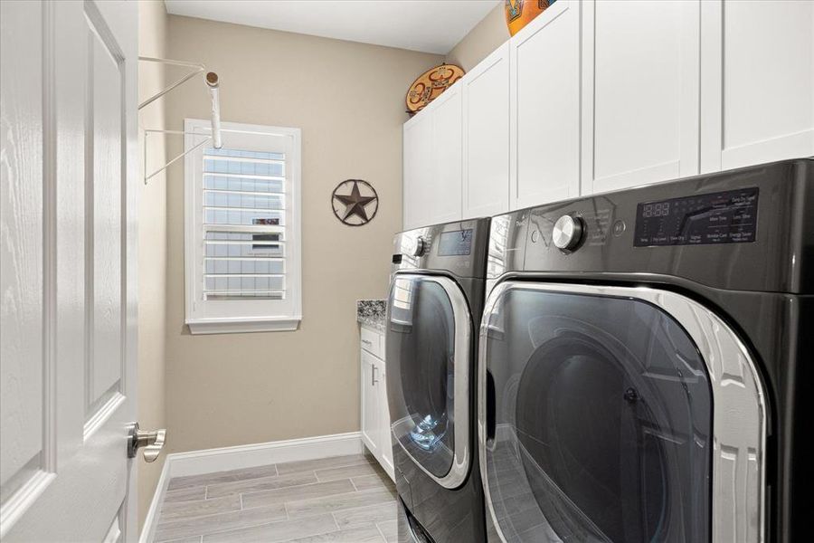Laundry room featuring wood tiled floors, washing machine and clothes dryer, and cabinet space Laundry room featuring wood tiled floors, washing machine and clothes dryer, and cabinet space