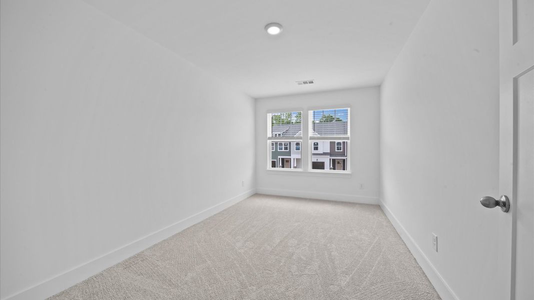 Plush carpeted bedroom with large windows in two story townhome at Ransdell Pointe by DRB Homes in Spartanburg, SC