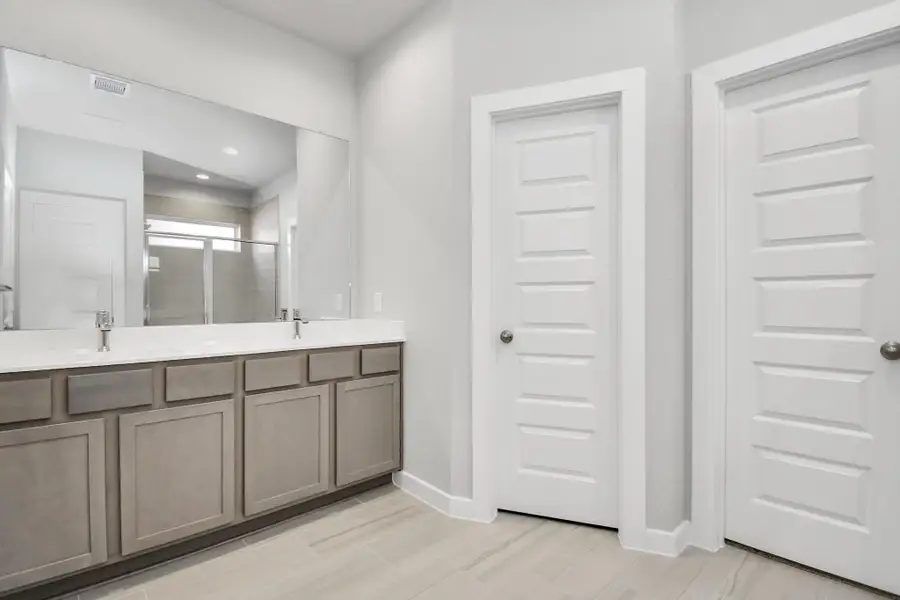 Immerse yourself in a luxurious retreat within the confines of your main bathroom and elevate your daily routine at the refined vanity, now boasting double sinks, light-toned countertops, modern hardware, and captivating bright recessed lights. Sample photo of completed home with similar floor plan. Actual colors and selections may vary.