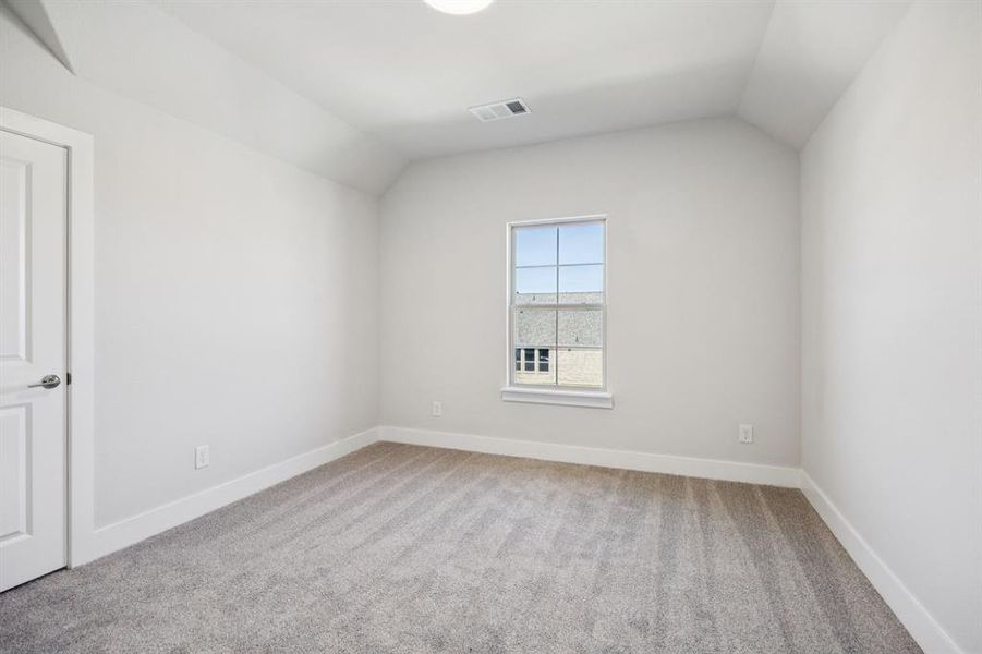 Empty room featuring light colored carpet and vaulted ceiling