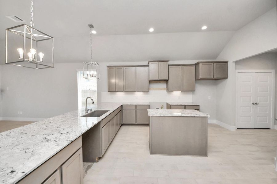 The kitchen is a culinary haven, featuring granite countertops, a tile backsplash, stainless steel appliances, 42” upper cabinets, and undercabinet lighting. Sample photo of completed home with similar floor plan. Actual colors and selections may vary.