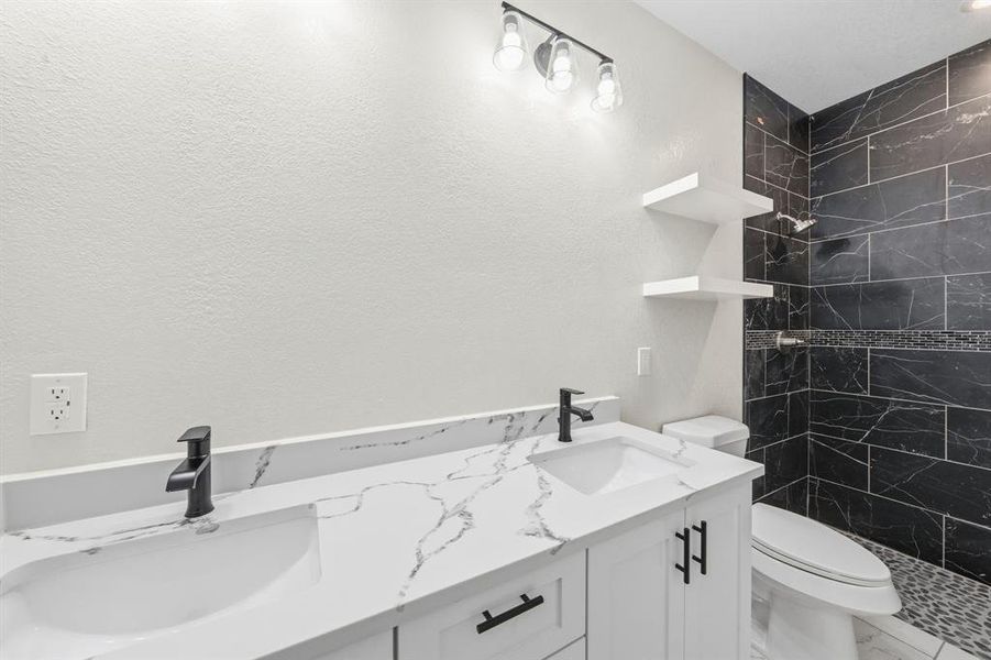 Full bathroom with double vanity and a shower stall