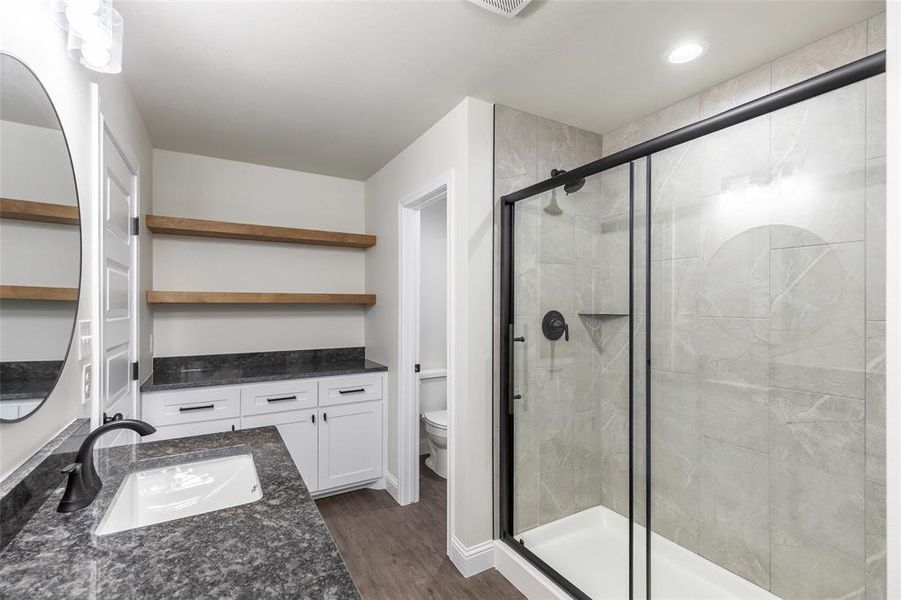 Bathroom featuring a single vanity with dark stone countertop, undermount sink, and matte black faucet