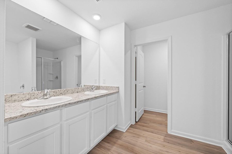 Bathroom with a shower stall, double vanity, light wood-type flooring, and recessed lighting