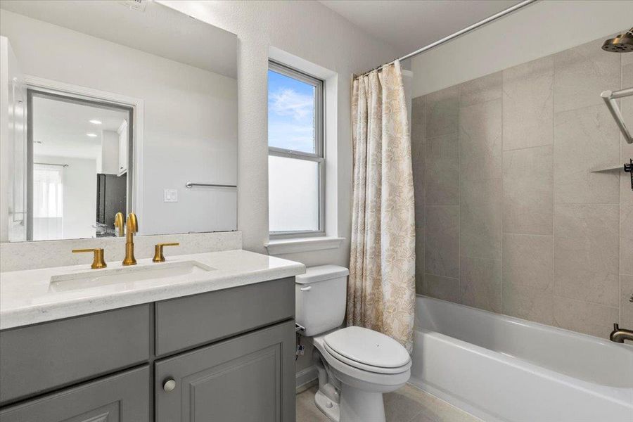 Bathroom with plenty of natural light, shower / bath combination with curtain, vanity, and light tile patterned floors Bathroom with plenty of natural light, shower / bath combination with curtain, vanity, and light tile patterned floors
