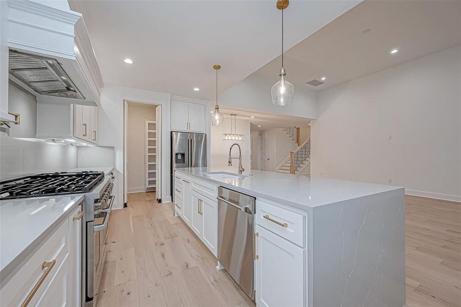 Kitchen with white cabinetry, stainless steel appliances, and a large island with quartz countertop.